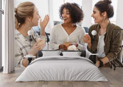 Happy young women friends having coffee break Wall mural