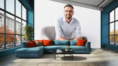 horizontal portrait of attractive caucasian guy wearing stylish formal clothing sitting in armchair  Wall mural