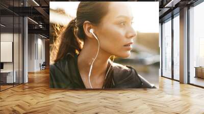 Image closeup of young sporty woman using earphones while working out Wall mural