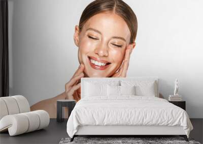 Image of adorable half-naked woman smiling at camera with eyes closed and touching her face Wall mural