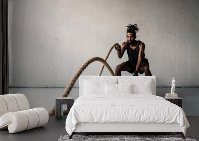 Image of african american sportsman working out with battle ropes Wall mural