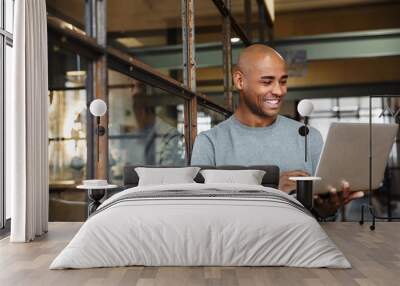 Image of bald african american man holding laptop while working in office Wall mural