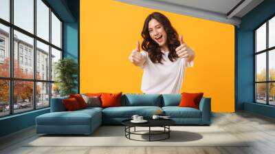 Image of beautiful brunette woman wearing casual clothes winking and showing thumbs up at camera Wall mural