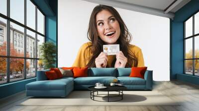 Image of caucasian brunette woman wearing casual clothes smiling and holding credit card Wall mural