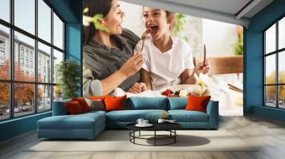 Image of caucasian family mother and little daughter eating tasty food together while having breakfast at home in morning Wall mural