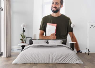 Image of caucasian happy man holding brochure and smiling Wall mural