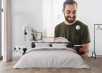 Image of caucasian happy man reading brochure and smiling Wall mural