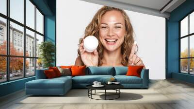 Image of cheerful half-naked woman showing facial cream and smiling Wall mural