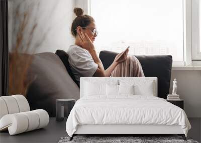 Image of concentrated woman using cellphone while sitting on sofa Wall mural