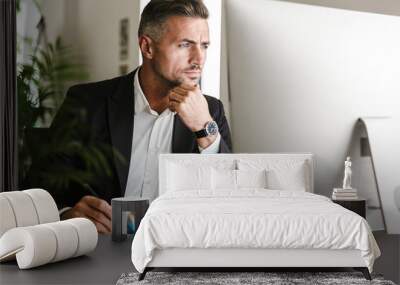 Image of confident businessman working in office and looking on computer Wall mural