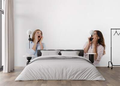 Image of excited caucasian two women screaming and looking upward Wall mural