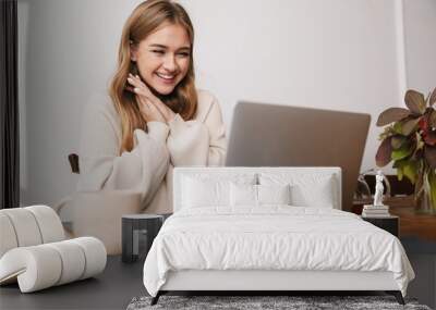 Image of excited young woman using laptop and drinking tea Wall mural