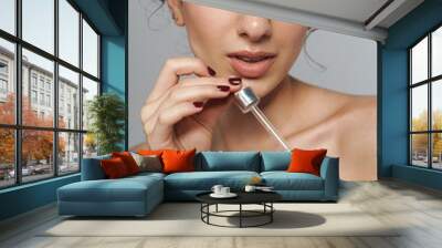 Image of half-naked woman with curly hair applying facial serum Wall mural