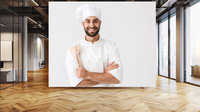 Image of happy chief man in cook uniform smiling while holding wooden kitchen utensils Wall mural