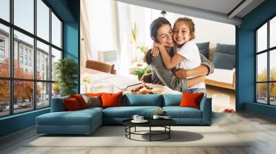 Image of happy family mother and little daughter hugging while having breakfast at home in morning Wall mural