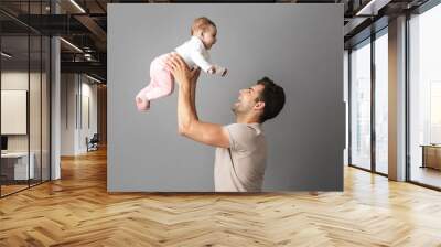 Image of happy father man holding his little child in hands, isolated over gray background Wall mural