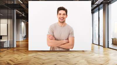 Image of happy smiling man 30s with bristle posing on camera with hands crossed, isolated over white background Wall mural