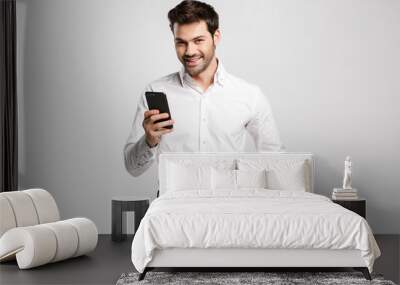 Image of happy successful businessman typing on cellphone and smiling Wall mural