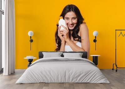 Image of happy woman in swimsuit holding sunscreen and smiling Wall mural