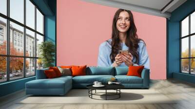 Image of joyful young woman looking upward and using cellphone Wall mural