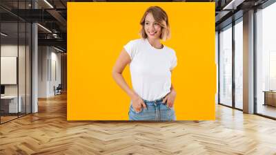 Image of lovely woman in basic t-shirt smiling and looking aside Wall mural