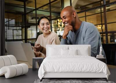 Image of multiethnic young coworkers working on laptops in office Wall mural