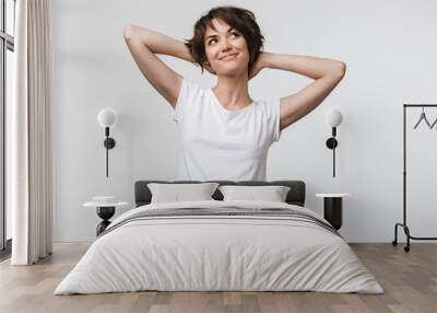 Image of optimistic woman in basic t-shirt touching her hair and looking aside Wall mural