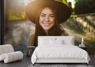 Image of satisfied woman smiling while walking in green park outdoors Wall mural