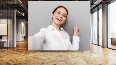 Image of successful redhead businesswoman 20s in formal wear smiling at camera while taking selfie photo Wall mural