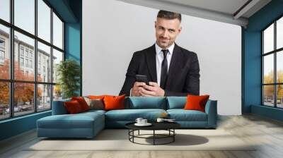 Image of successful unshaven businessman in formal suit typing on cellphone and looking at camera Wall mural