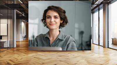 Image of young beautiful joyful woman smiling while working with laptop Wall mural