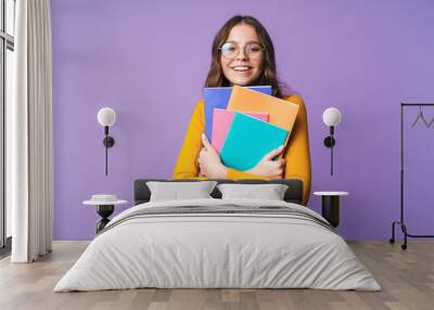 Image of young beautiful student girl smiling and holding exercise books Wall mural