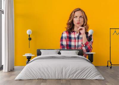 Image of young beautiful woman wearing plaid shirt expressing concern Wall mural