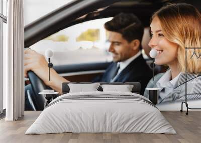 Image of young caucasian businesslike man and woman riding in car Wall mural