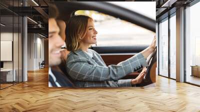 Image of young caucasian businesslike man and woman riding in car Wall mural