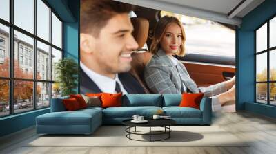 Image of young caucasian businesslike man and woman riding in car Wall mural