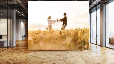 Image of young caucasian couple dancing in golden field on countryside Wall mural