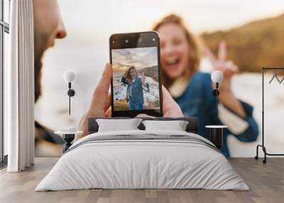 Image of young caucasian couple taking photo on cellphone by seaside Wall mural