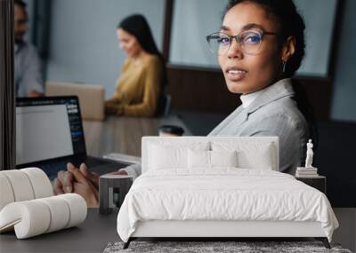 Image of young female and male colleagues working on laptops in office Wall mural