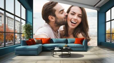 Image of young happy man kissing and hugging woman while taking selfie Wall mural