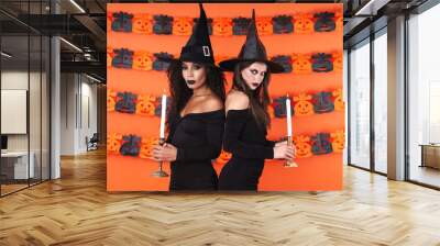 Image of young witch women in black halloween costume holding candles Wall mural