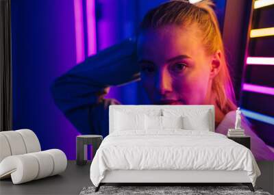 Image of young woman standing by multicolored neon illumination indoors Wall mural