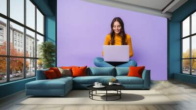 Image of young woman using laptop while sitting with legs crossed Wall mural