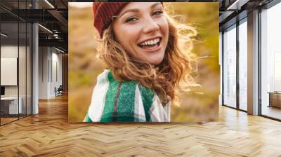 Image of young woman wearing hat and plaid shirt walking outdoors Wall mural