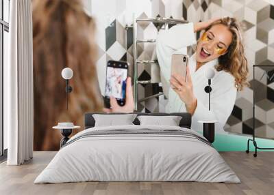 Image of young woman with eye patches taking selfie photo in bathroom Wall mural