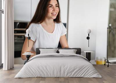 Joyful caucasian woman smiling while having lunch at home kitchen Wall mural