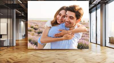 Joyful young couple having fun at the lavender field together Wall mural