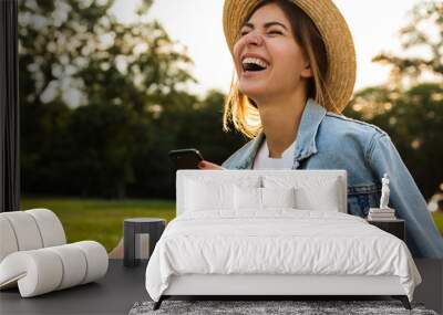 laughing young girl in summer hat sitting outdoors Wall mural