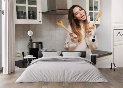 Lovely young woman cooking while standing Wall mural