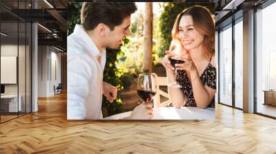 Loving couple sitting in cafe by dating drinking wine Wall mural